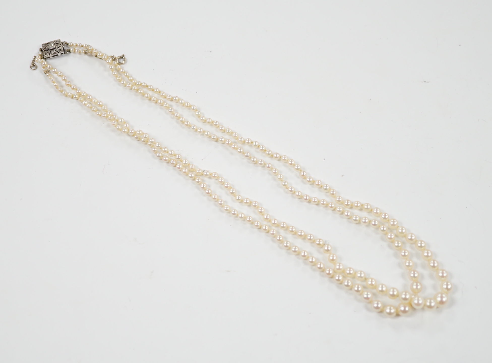 A 1940's French double strand graduated cultured pearl necklace, with diamond set white metal clasp (18ct poincon mark), 46cm.